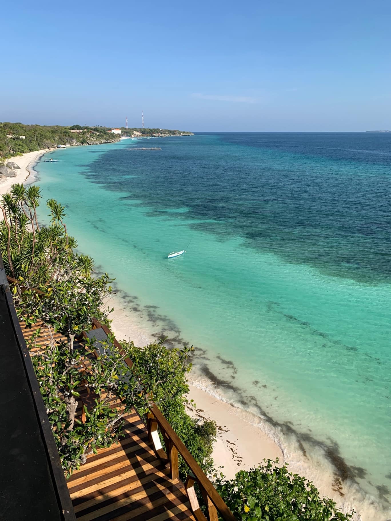 The view from the cliff above Bara Beach, looking out over the shallow turquoise bay towards the Flores Sea