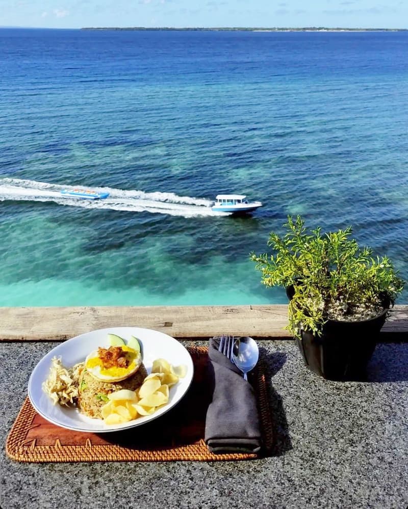 Breakfast fried rice with krupuk on the deck rail, the sea and a passing boat below