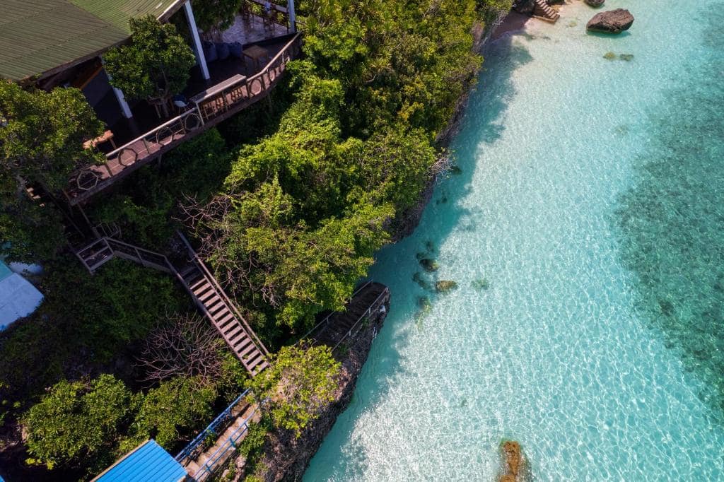 Aerial view of the Bara Beach coastline at Tanjung Bira — white sand, turquoise shallows and the low cliff where Seascapes Bira stands