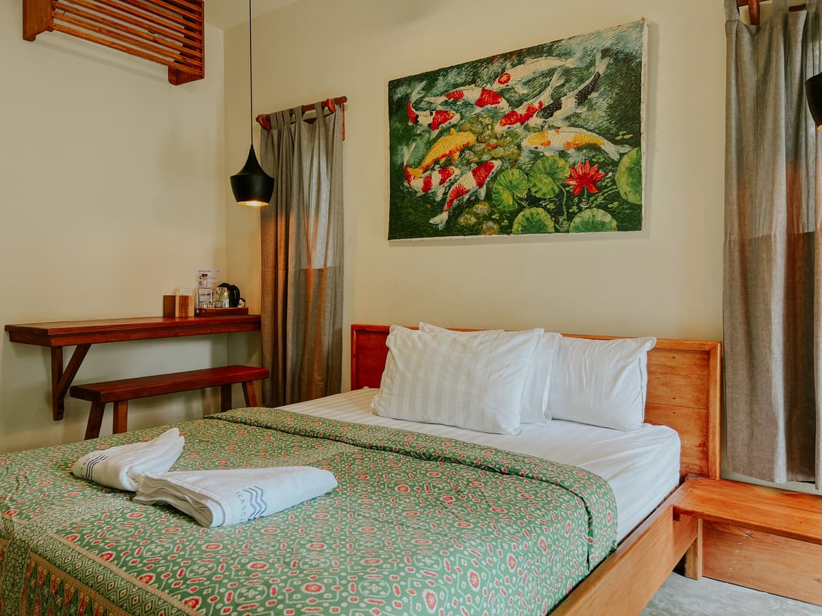 Kapas room: queen bed with a green batik cover under a koi painting