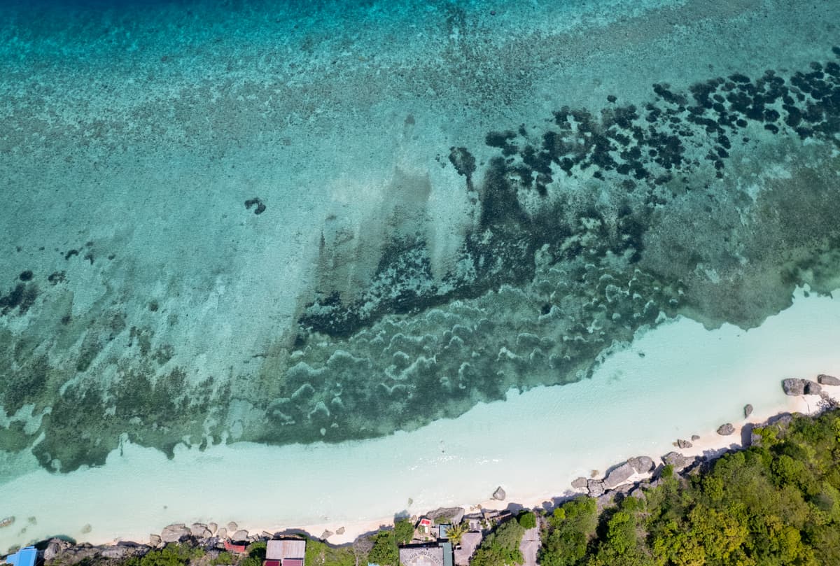 Reef and white sand from directly above, the shore at the bottom edge